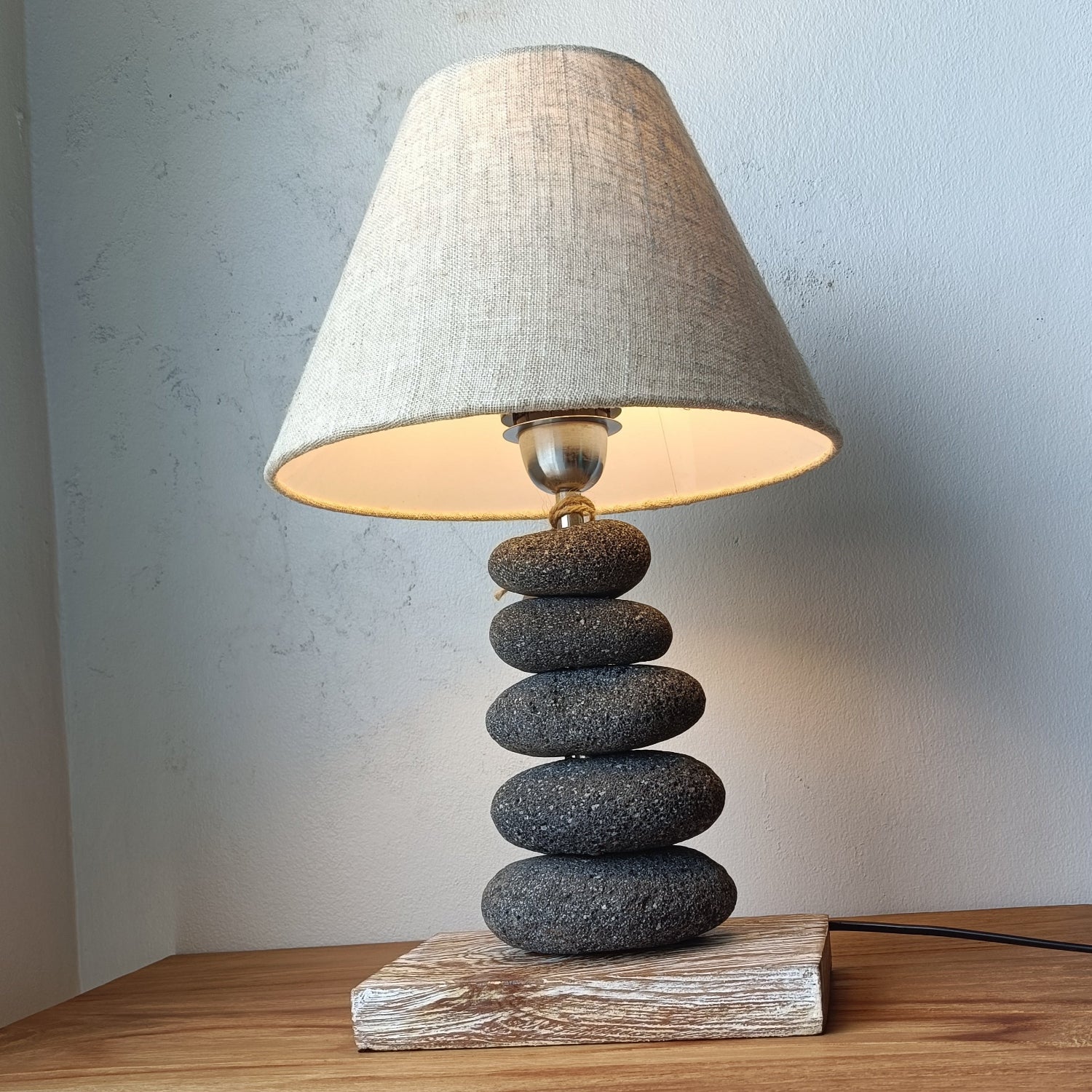 Table lamp with stone base and gray shade on a wooden surface