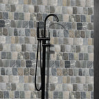 Black shower faucet against a mosaic tile wall with various shades of gray and beige.