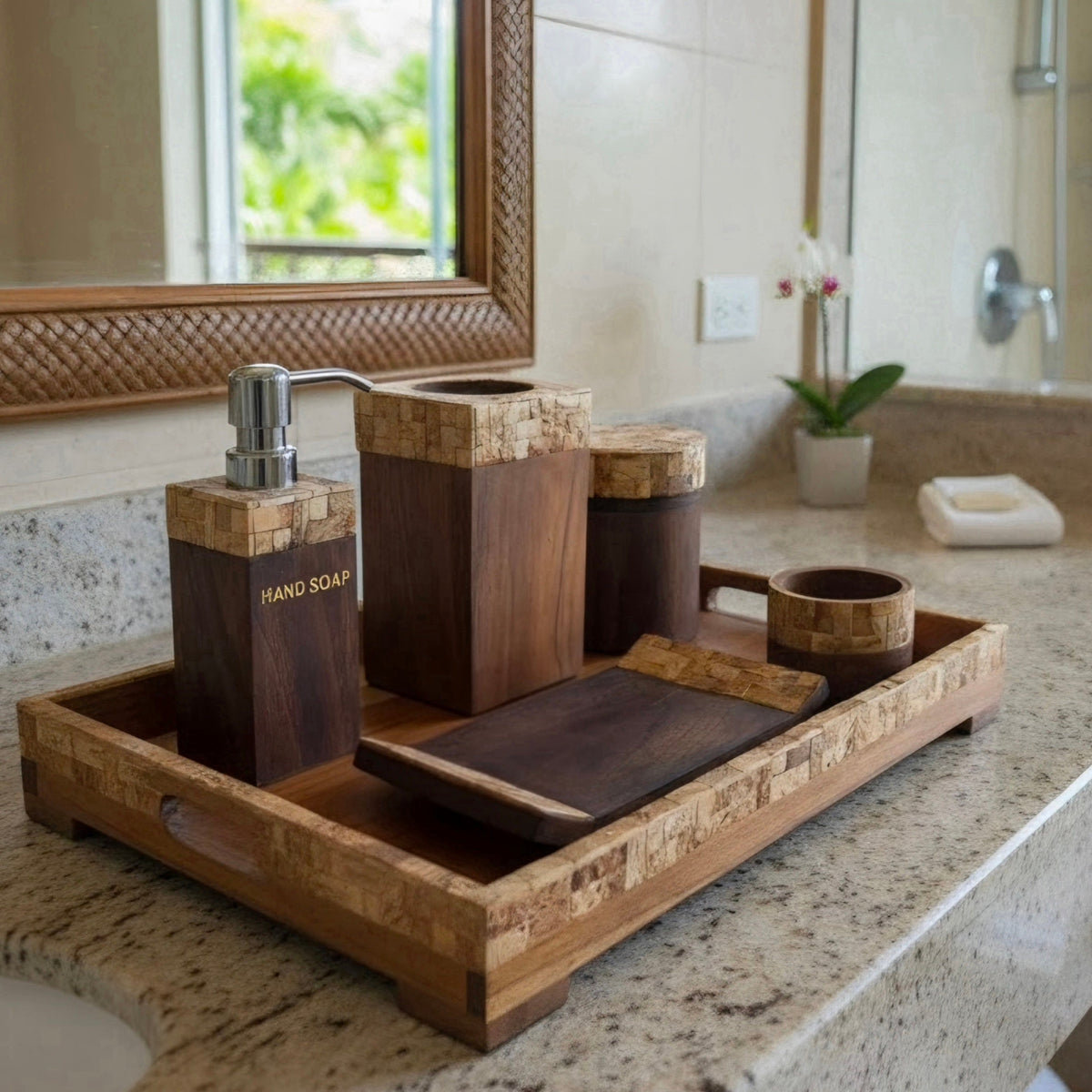 A bathroom vanity set made of dark wood and coconutshell, including a hand soap dispenser, a soap dish, a jar, a cup, and a tray, arranged on a granite countertop.