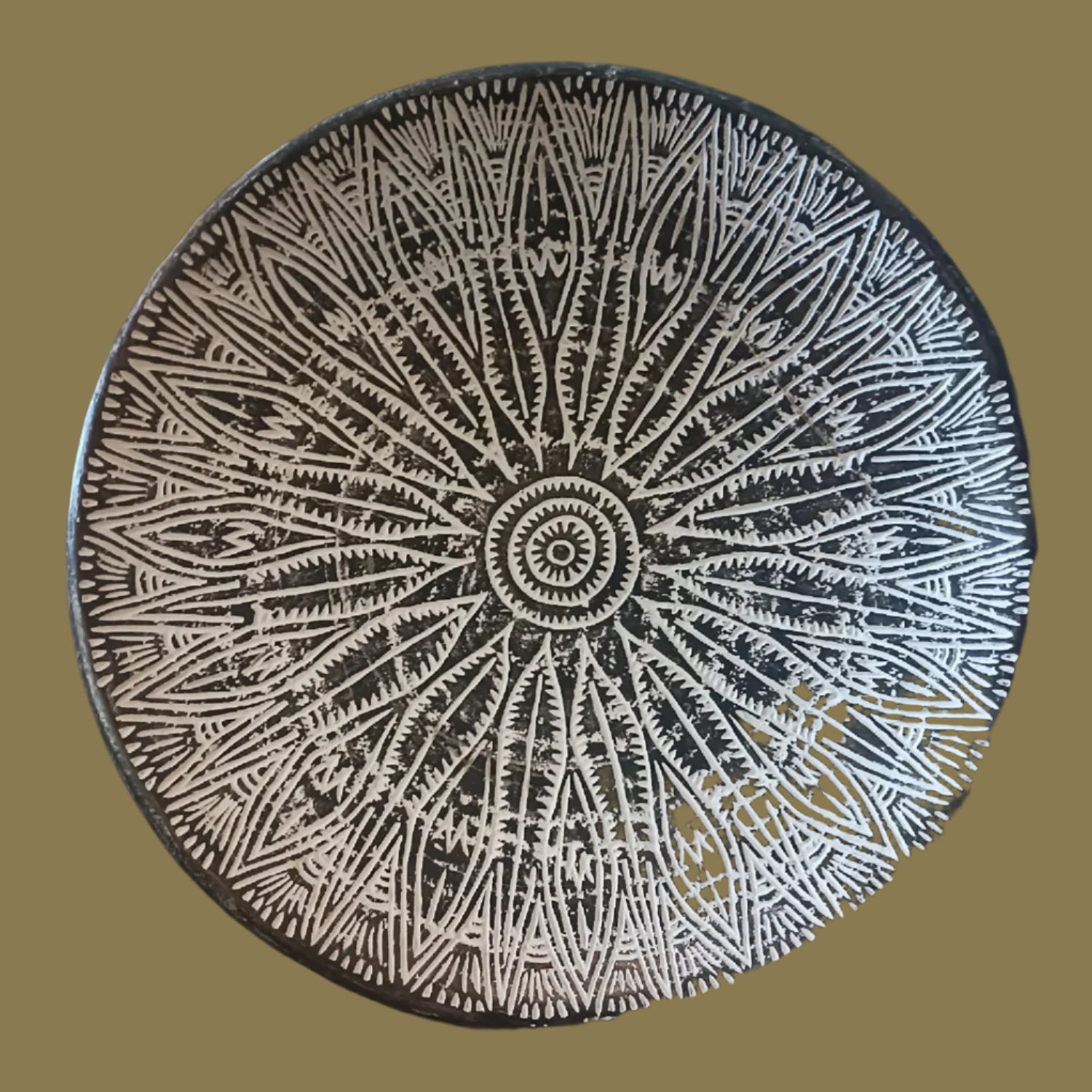 A hand-carved wooden decorative plate with a geometric pattern, predominantly in a black and white color palette.