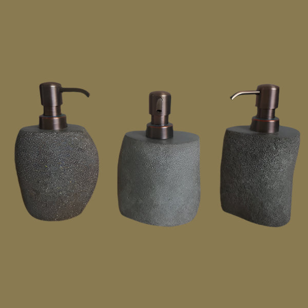 Three stone-textured soap dispensers with bronze pumps.