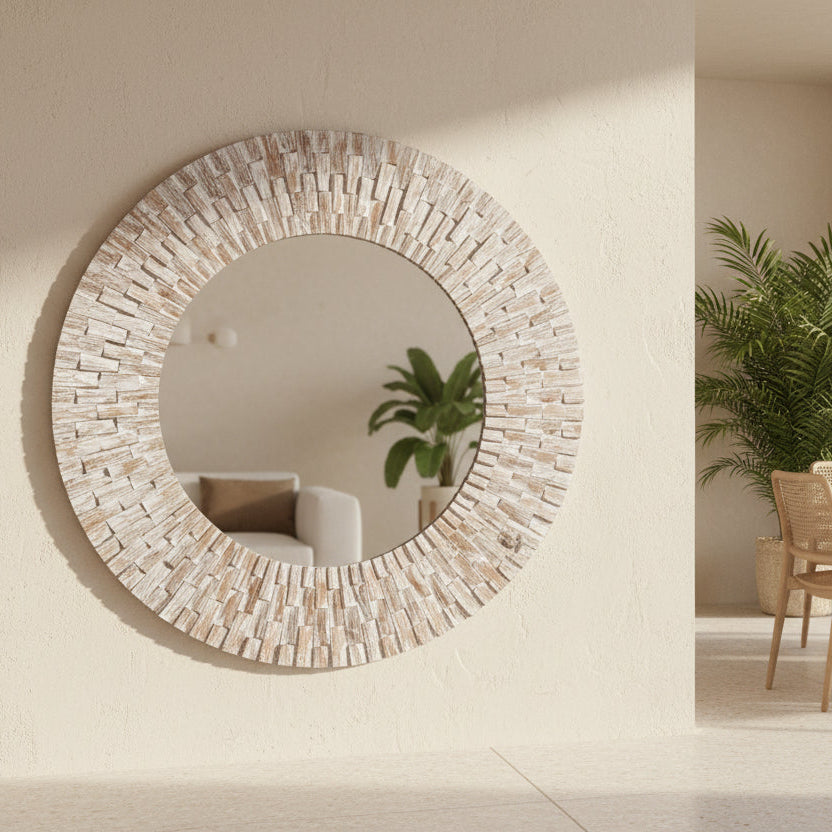 Round decorative mirror frame 
in whitewashed wood on a wall.
