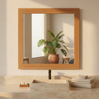 Large teak wooden-framed mirror reflecting a bedroom interior with a bed and decor.