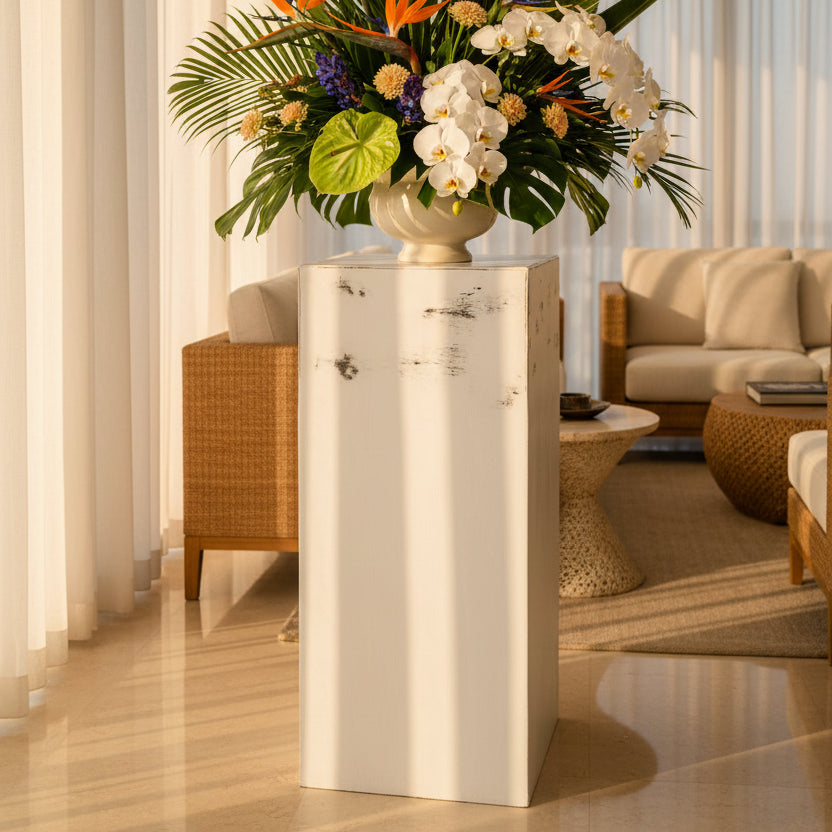 Potted plant on a pedestal with a view of a balcony and sunset.