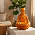 Orange Saolin monk statue on a table with a plant and furniture in the background