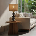 Table lamp with stone base and woven shade on a wooden surface.