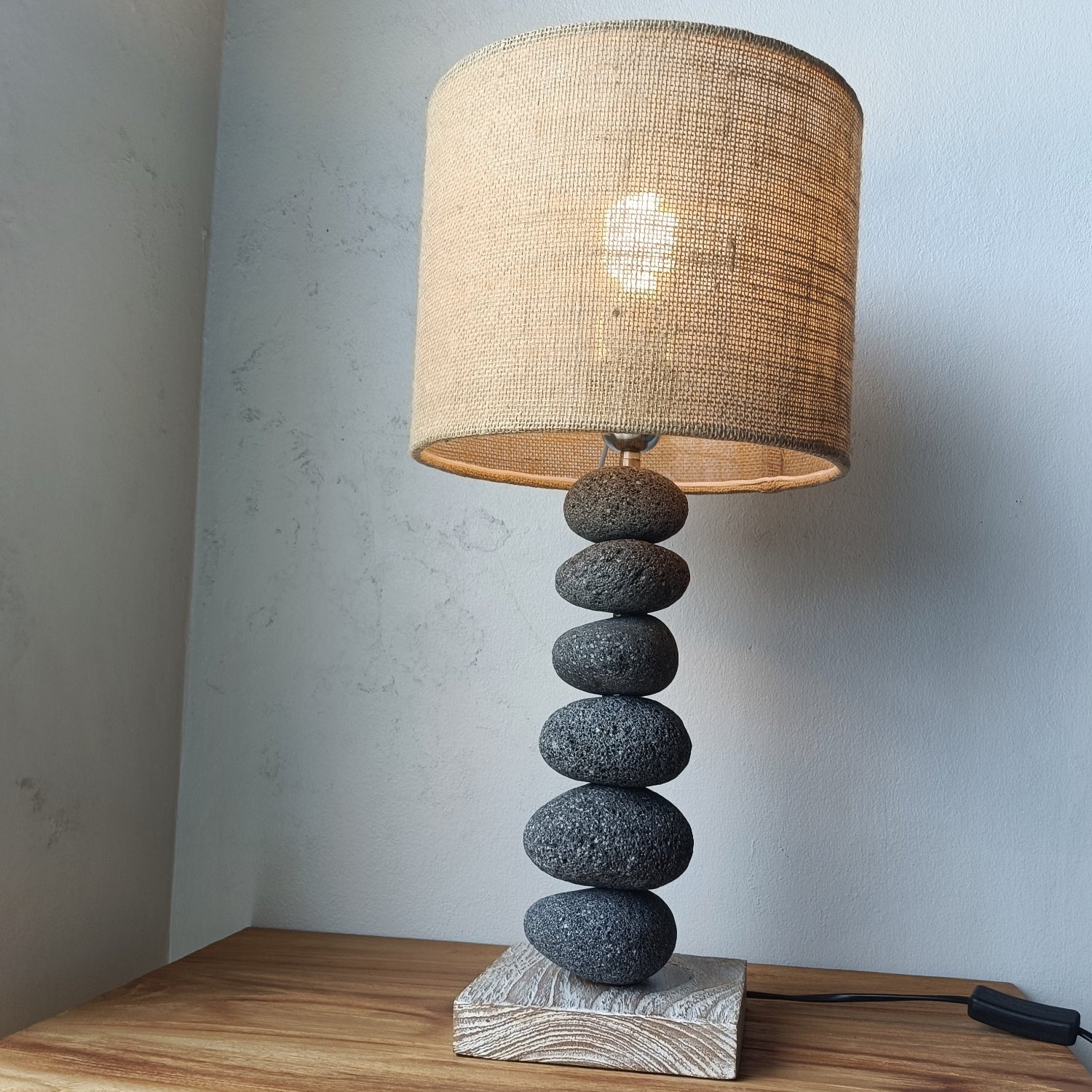 Table lamp with stone base and woven shade on a wooden surface.