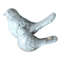 A pair of decorative homing pigeons, one larger than the other, with a grayish-white color and textured surface.