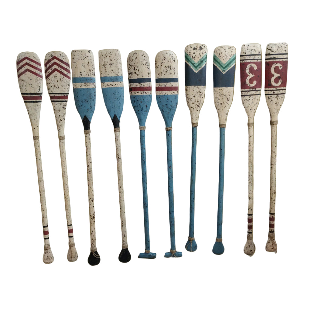 Set of decorative wooden oars with speckled handles and striped blades.