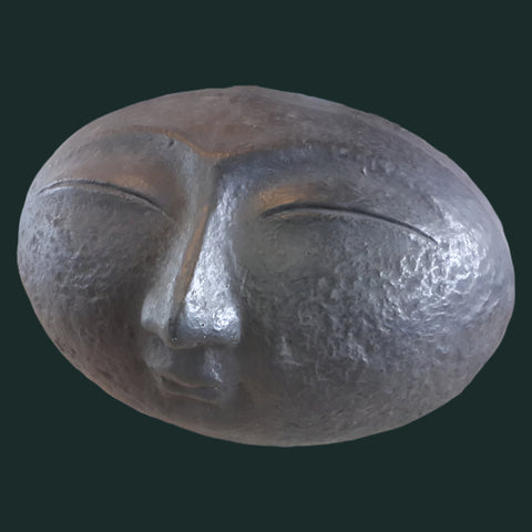 A sculpture of a smiling face with closed eyes, finished in black paint.